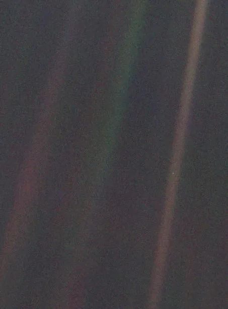 A tiny pale speck in a streak of scattered sunlight against black space