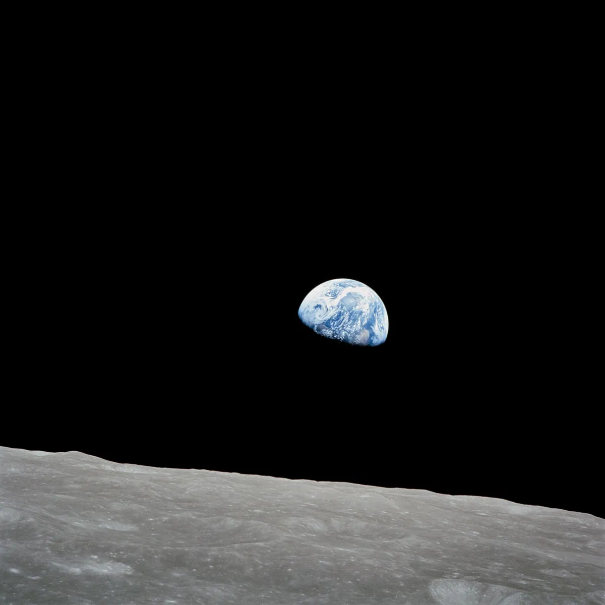 Earth rising above the grey horizon of the Moon
